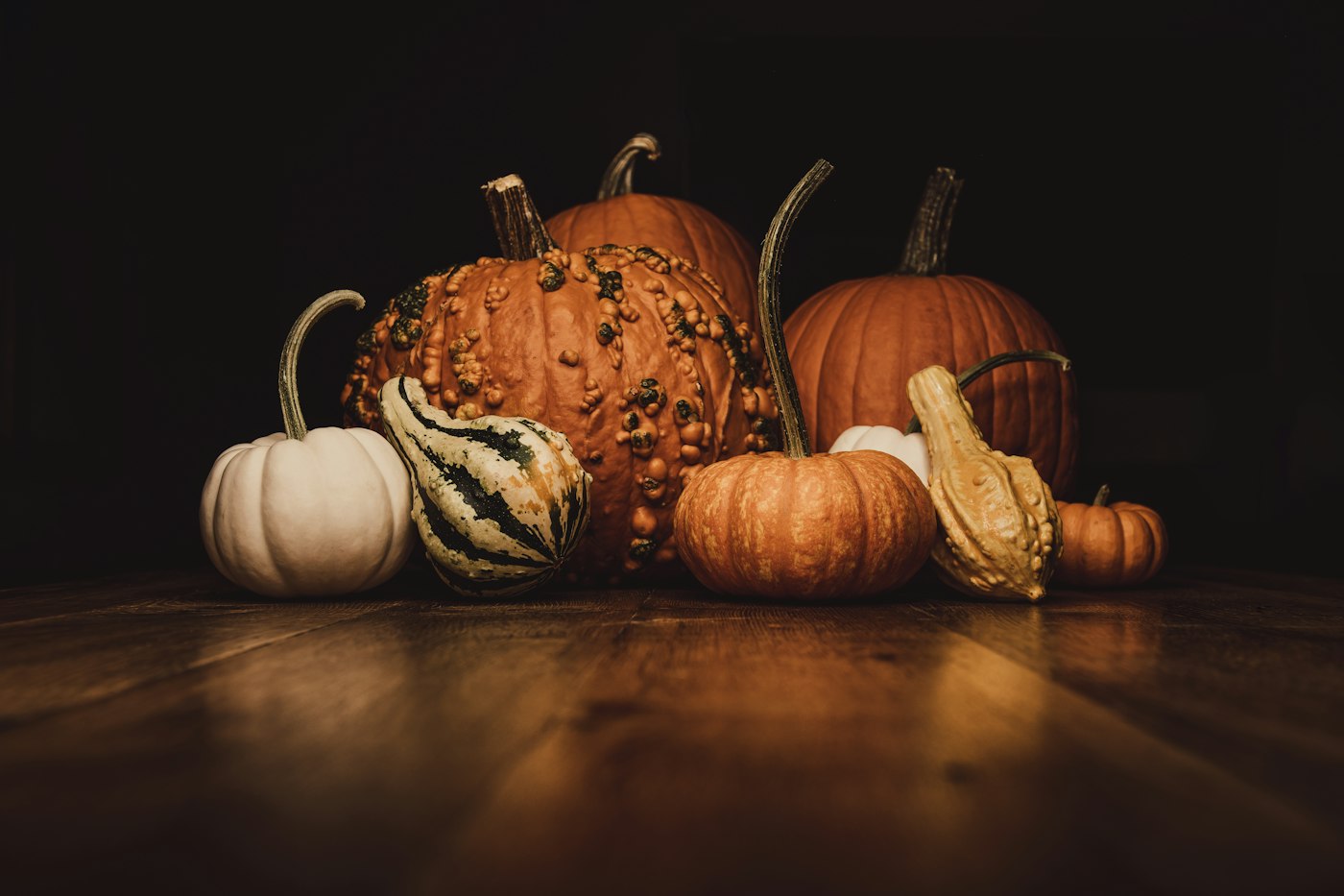 A pile of orange and white pumpkins on a wood table