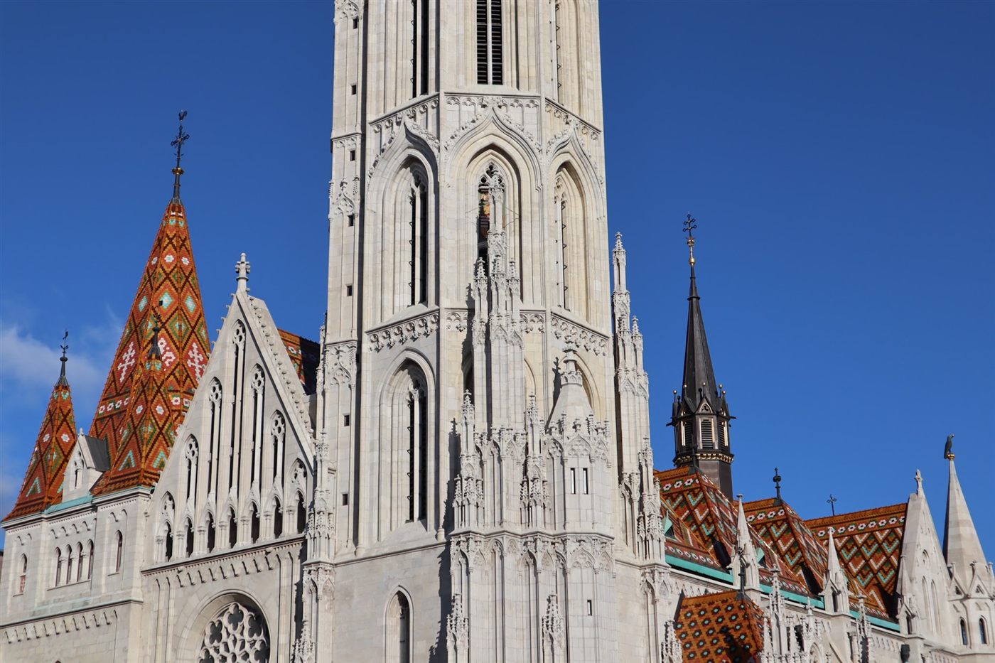 Diamond-patterned tile roofs and white Gothic tower of Matthias Church in Budapest