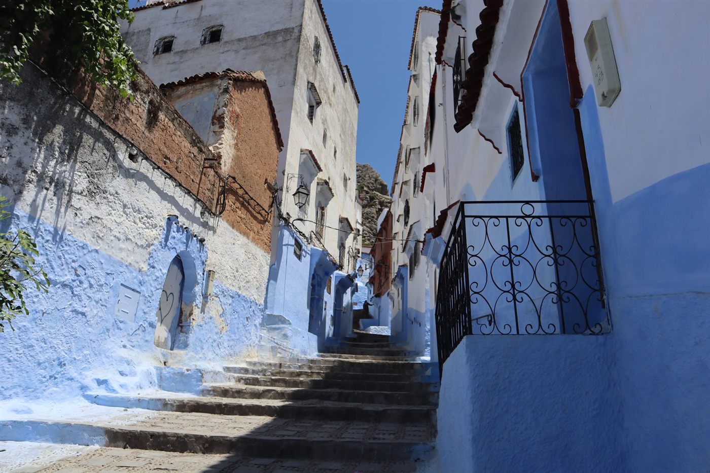 Blue-washed stairs and walls with a wrought-iron railing in Chefchaouen