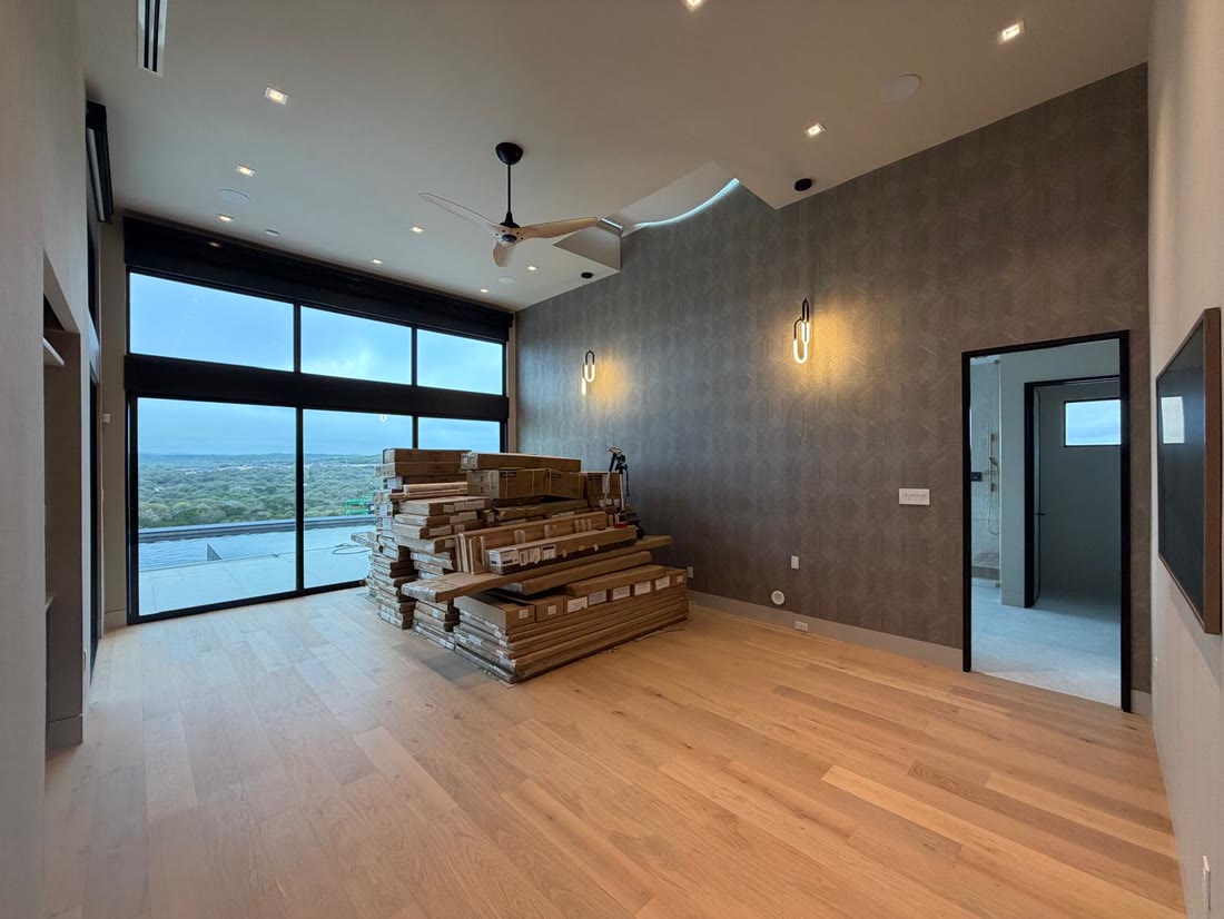 A bedroom with a patterned feature wall, pale oak floor and sliding glazing to the terrace