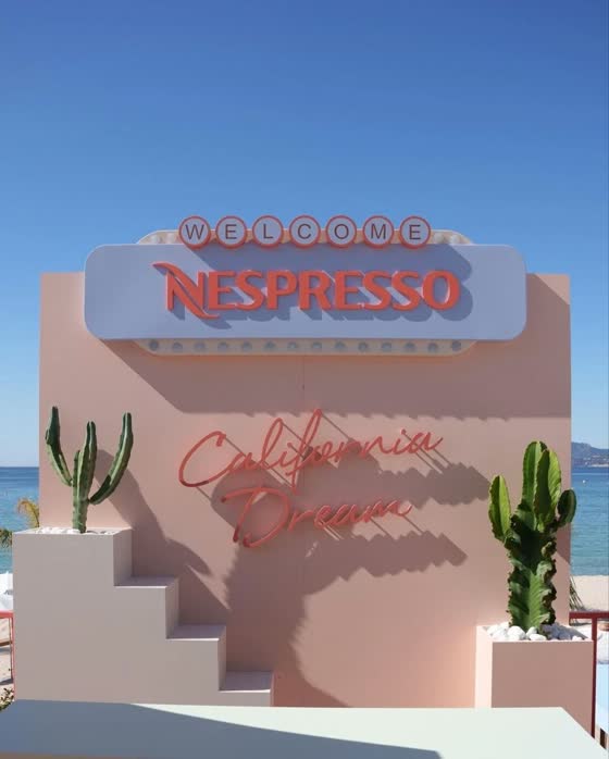 A pink stage set on a beach with a Welcome Nespresso marquee sign and cactus planters